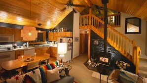 Ein gemütliches Interieur mit Holzbalkendecke, einem Essbereich, einem Wohnzimmer mit Kamin und einer Küche mit Holzausstattung.