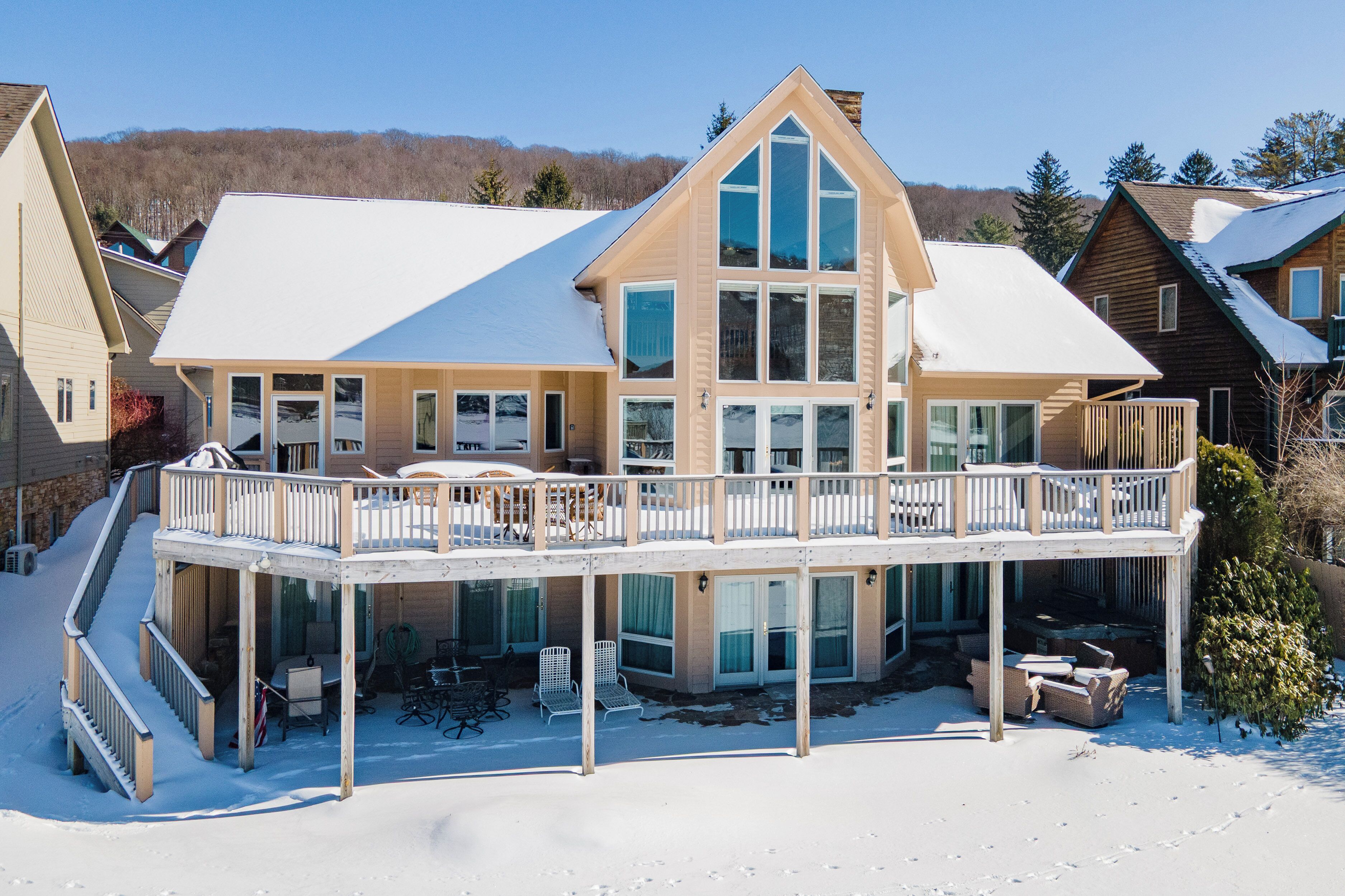 Une grande maison à plusieurs étages, dotée d’un balcon et d’une terrasse, entourée de neige.