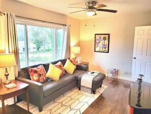 Relax in this inviting living room with a large sofa, ceiling fan, and framed artwork.