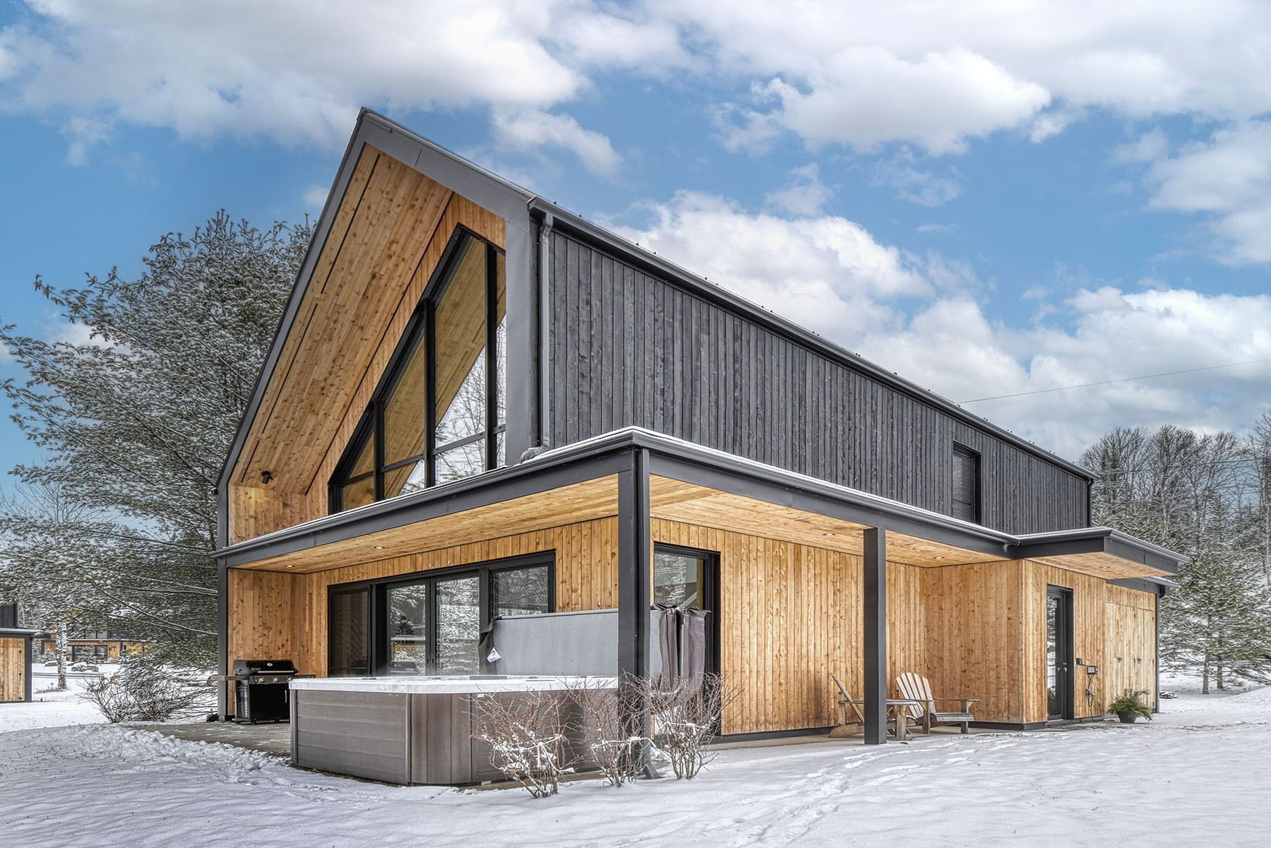 A modern two-story house with a sloped roof, large windows, and a wooden exterior.