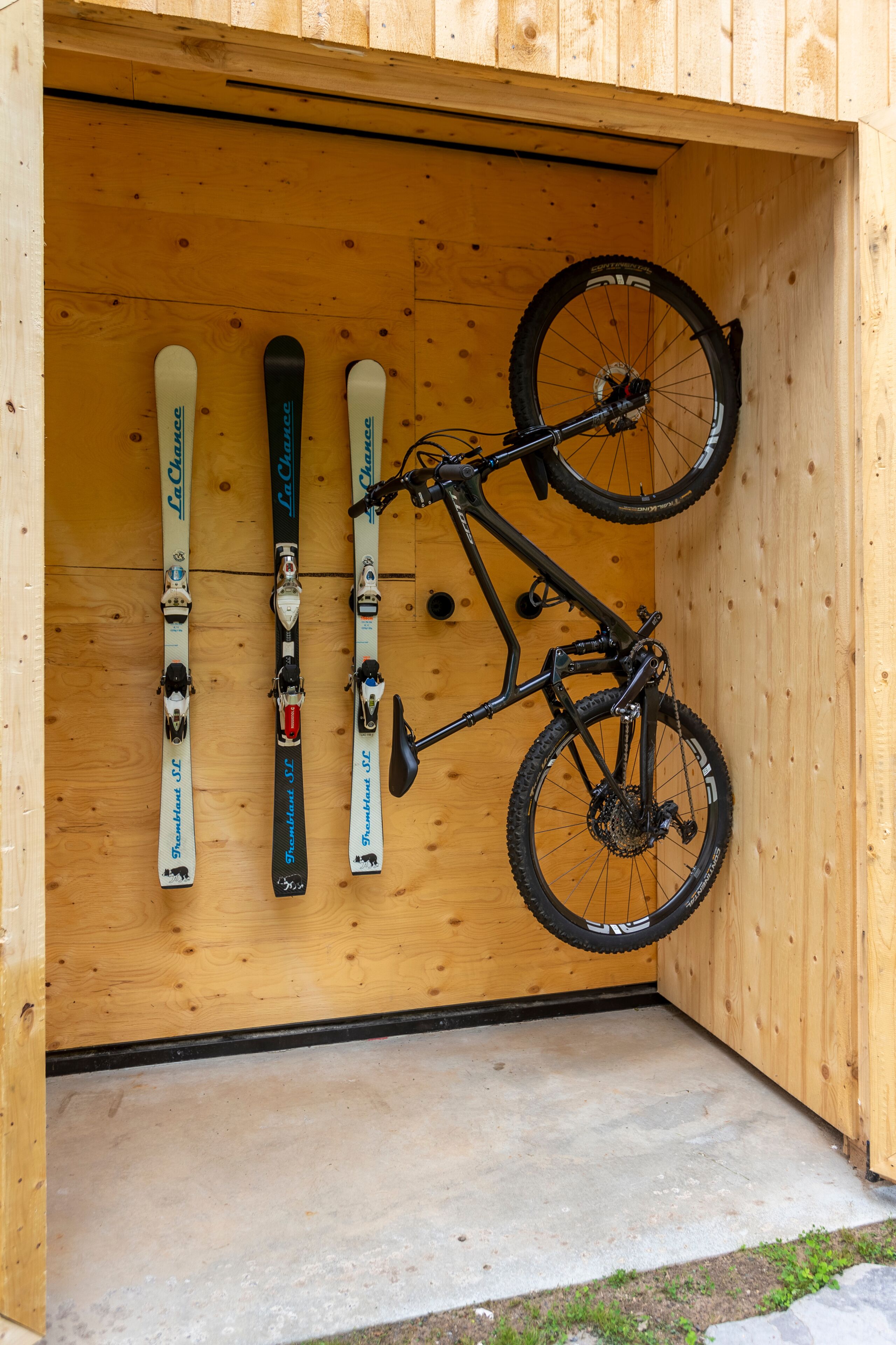 Eine Holzwand mit angenagelten Skiern und einem Fahrrad.