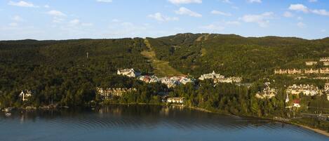 A lakeside town with buildings on a hillside, a clear sky, and calm water.