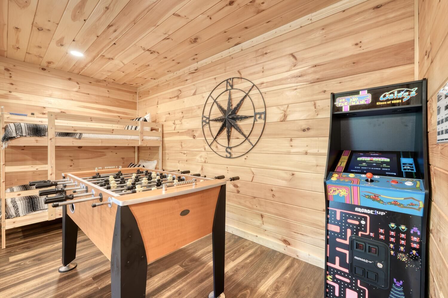 Une pièce au décor intérieur en bois, avec un baby-foot et une borne d’arcade rétro.