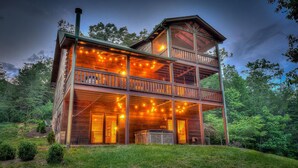 Eine zweistöckige Holzhütte mit Balkon, Lichterkette und Kamin.
