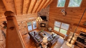 Eine Hütte mit Kamin aus Stein, Holzwänden, einer Ledersofa und einer Küchenzeile.