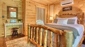 Ein Zimmer in einer Holzhütte mit einem Bett, einem Schreibtisch und einer Klimaanlage.