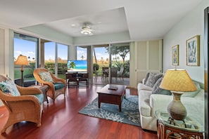A spacious living room with wicker furniture, a glass coffee table, and a view of the outdoors.