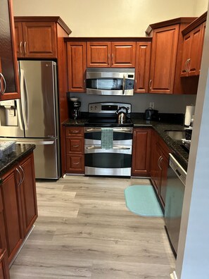 A kitchen with wooden cabinets, stainless steel appliances, and a granite countertop.