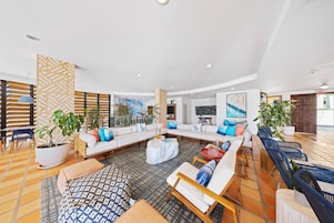 A spacious, well-lit living area with a large sectional sofa, multiple seating options, and potted plants.