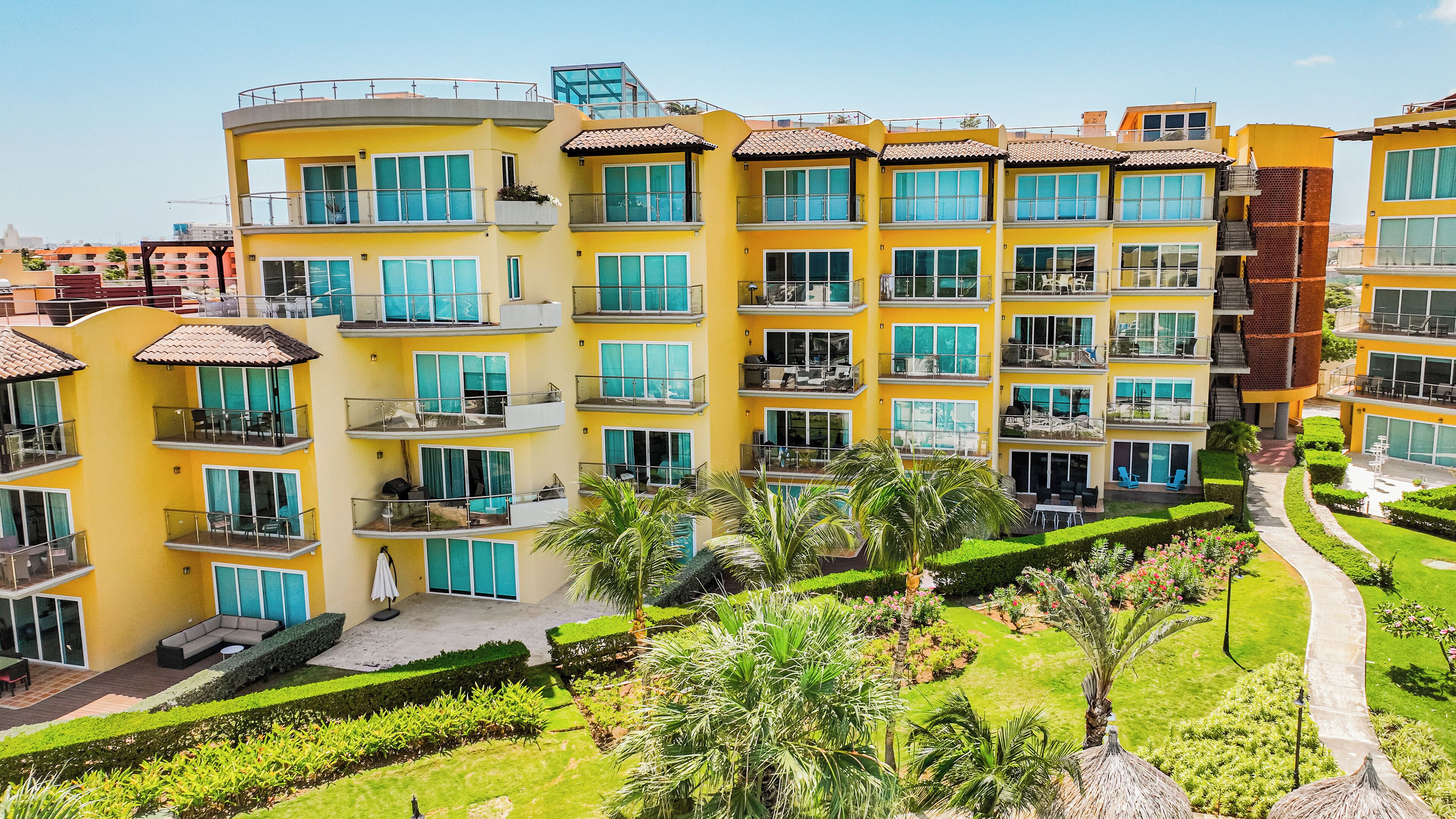 Un hotel de varios pisos con balcones, piscina y jardines bien cuidados.