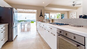A modern kitchen with a large island, stainless steel appliances, and a view to the outdoors. - Sombre 14-e (Santa Cruz)