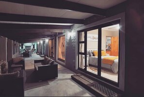 Enjoy a spacious room with a balcony offering views of the outdoor area, a comfortable bed, and a seating area with a sofa and desk.