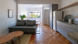 Una sala de estar moderna con un sofá gris, una mesa de centro de madera y vistas al exterior.