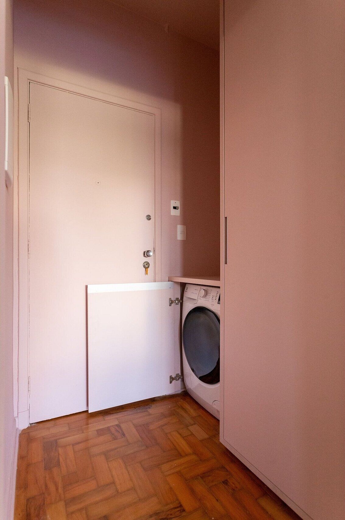 Uma lavanderia com máquina de lavar e uma porta.