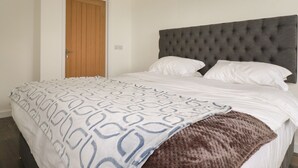 Ein Schlafzimmer mit einer gesteppten Kopfteil, einer gemusterten Bettdecke und einer braunen Tagesdecke.