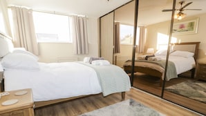 A hotel room with two beds, a wooden floor, a mirror, and a view of the outdoors. - Hilltops (Conwy)