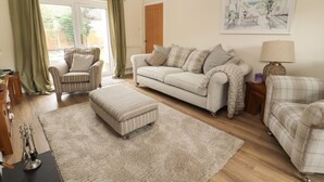 A living room with a sofa, armchair, ottoman, and a lamp. - Hilltops (Conwy)