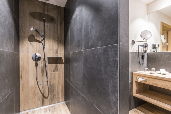 A modern bathroom with a wooden vanity, a mirror, and a shower with a handheld showerhead.