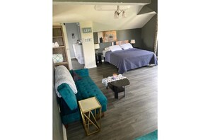 Cozy retreat with a neatly made bed, sofa, and wooden side table, perfect for relaxing.