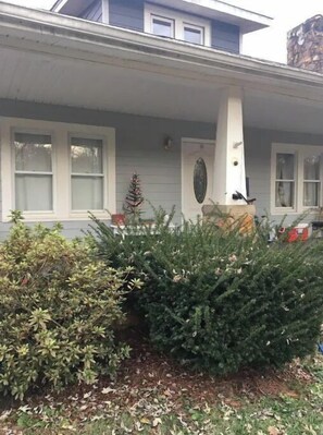 Guests can enjoy a porch with a column and decorative emblem, surrounded by lush greenery.
