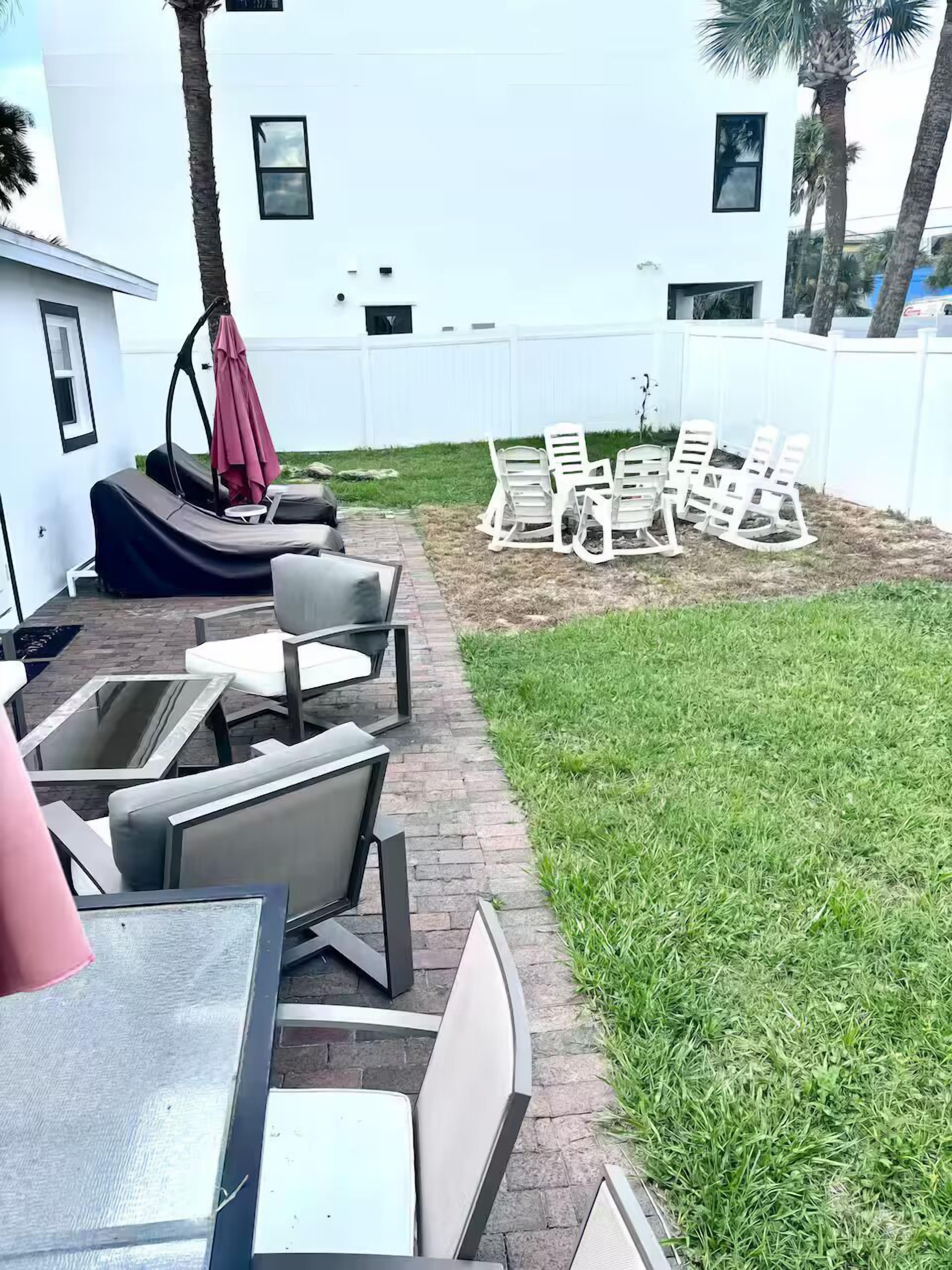Een terras met buitenmeubels, een schommelstoel en een witte hek.