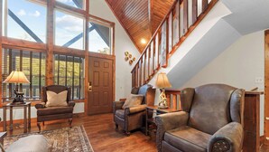 Un vaste salon doté d’un plancher en bois, d’un plafond haut et d’un escalier menant à l’étage supérieur.