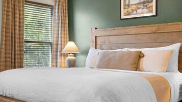 A neatly made bed with a wooden headboard, a bedside lamp, and a framed picture on the wall.