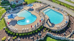 Un gran complejo turístico con múltiples piscinas, una tobogán acuático central, rodeado de zonas de descanso y un edificio grande al fondo.