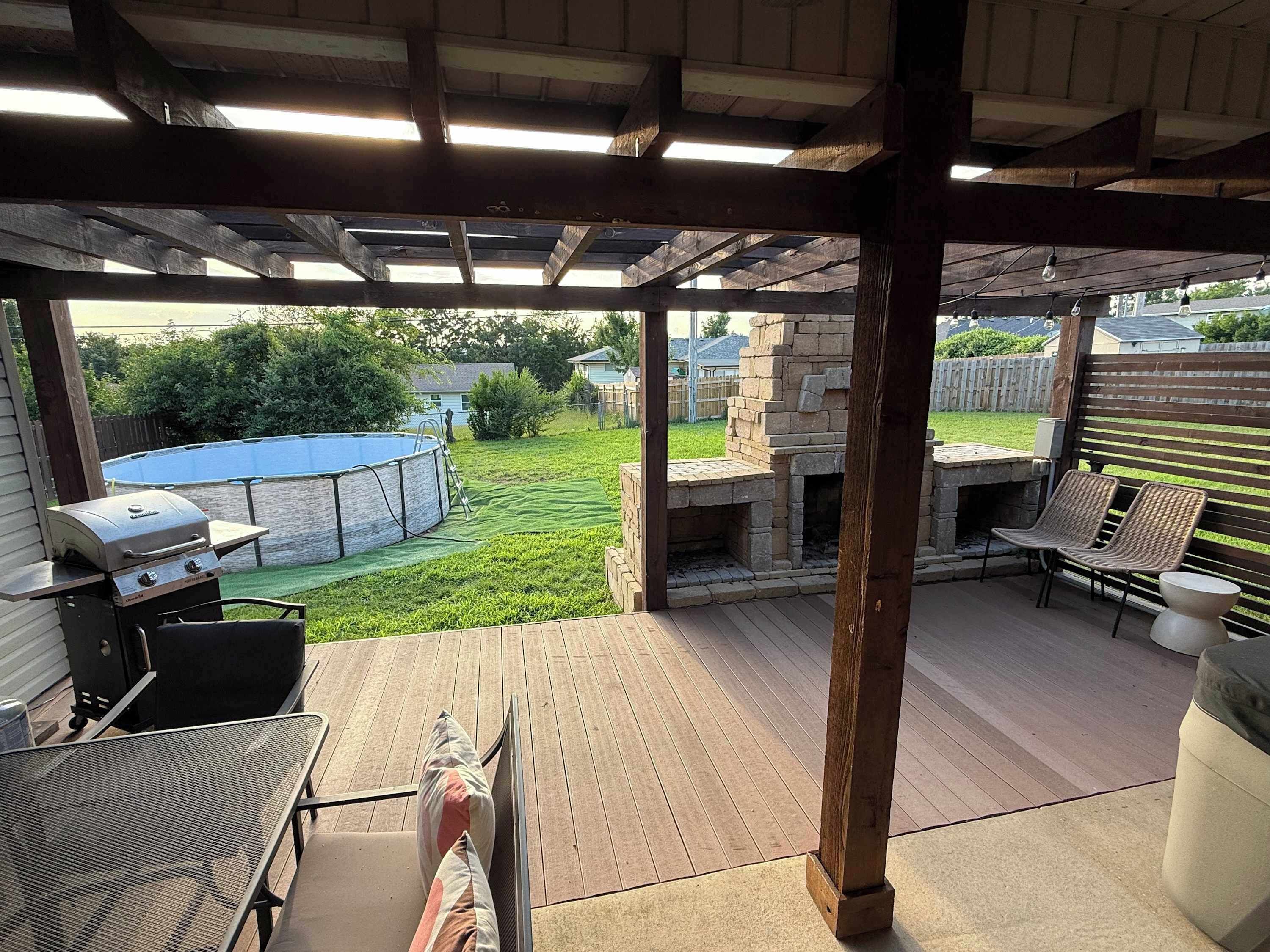 An outdoor patio with a grill, seating, and a stone fireplace.
