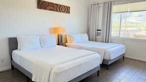 A hotel room with two beds, a lamp, a painting on the wall, and a window with curtains. - Waena Inn #14 Private Studio w/2 queen beds (Wailuku)
