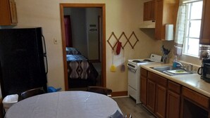 Una cocina compacta con armarios de madera, una mesa redonda para comer y un refrigerador.