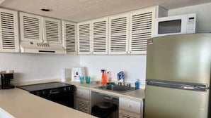A compact kitchen with a stainless steel refrigerator, a microwave, a stove, and a sink. - Beachfront Condo at Club de Yates (Puerto Aventuras)