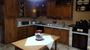 Une cuisine avec des meubles de rangement en bois, une cuisinière à gaz, un évier et une table sur laquelle est posé un vase.