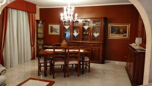 Un coin repas avec une table et des chaises en bois, un lustre et un buffet aux portes vitrées.