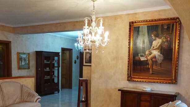 Un salon spacieux agrémenté d’un lustre, d  ’un tableau et d’un canapé.