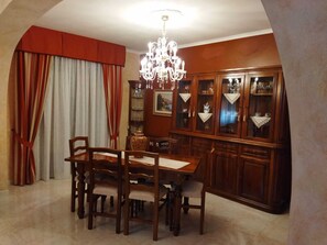 Un coin repas avec une table et des chaises en bois, un lustre et un buffet.