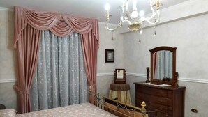 Une chambre à coucher avec un lit, une commode, un miroir et un lustre.