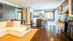 Un salon moderne avec un canapé blanc, un plancher en bois et une cuisine en arrière-plan.