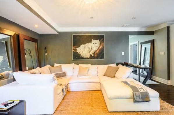 A modern living room with a large sectional sofa, a flat-screen TV, and a framed artwork on the wall.