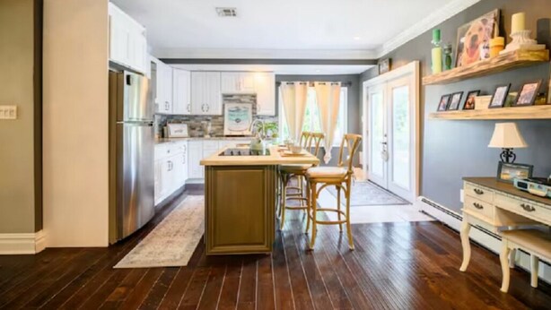 Une cuisine avec un îlot central, des chaises en bois, une table à manger et un réfrigérateur.