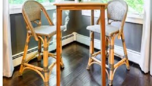 Una habitación con dos sillas de mimbre, una mesa de madera y una planta en maceta.