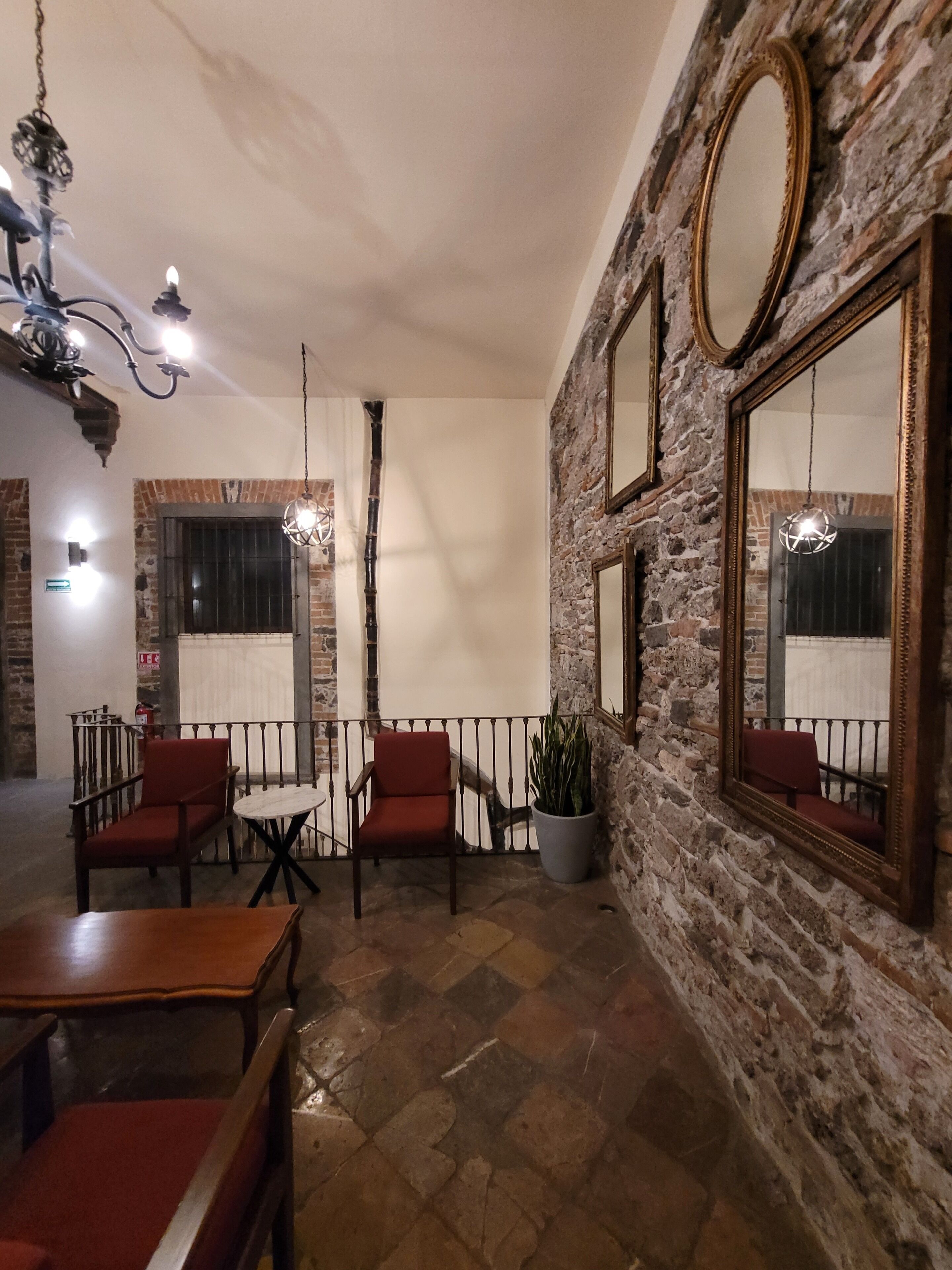 A cozy interior with stone walls, a round mirror, and a table with chairs.