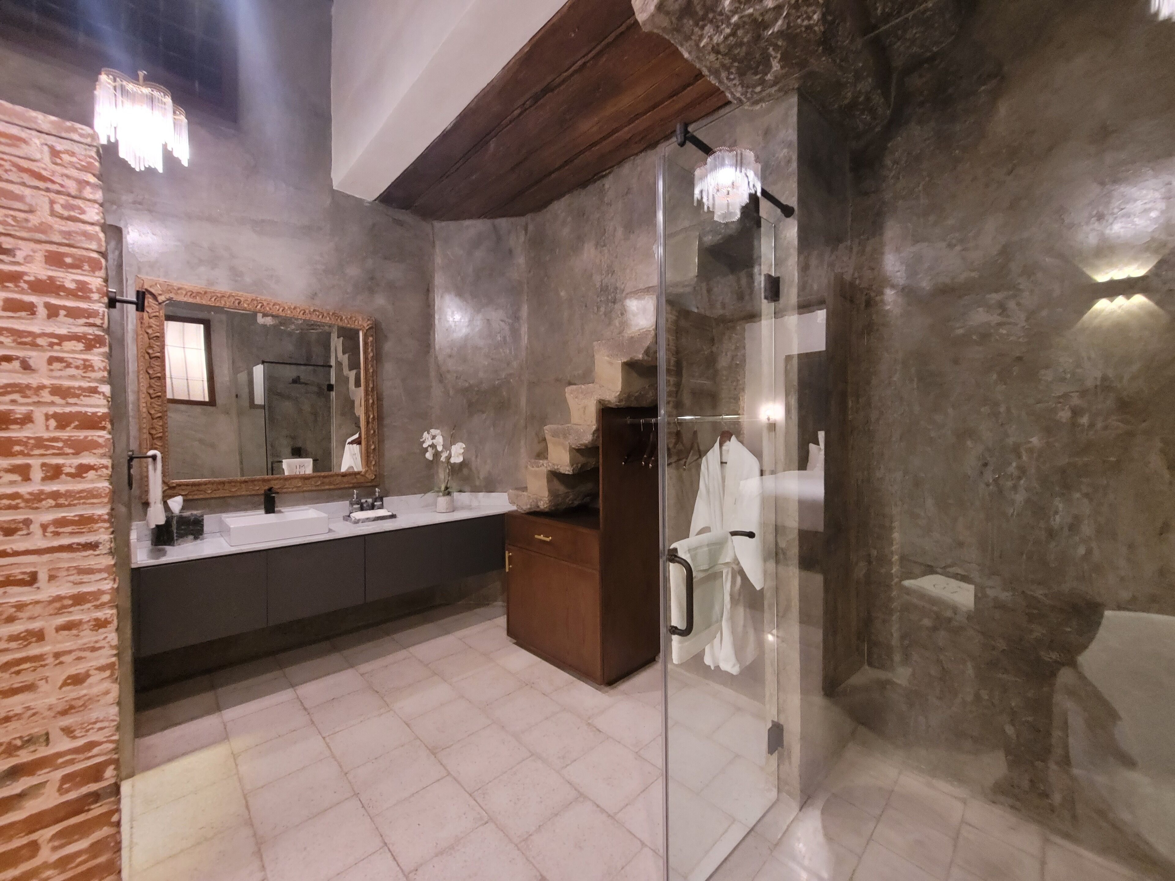 A modern bathroom with a large mirror, a sink, and a glass shower enclosure.
