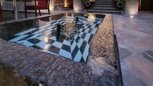 A spacious lobby with a checkered floor, a red chair, a staircase, and stone walls. - Milo Collection Hotel (Puebla)
