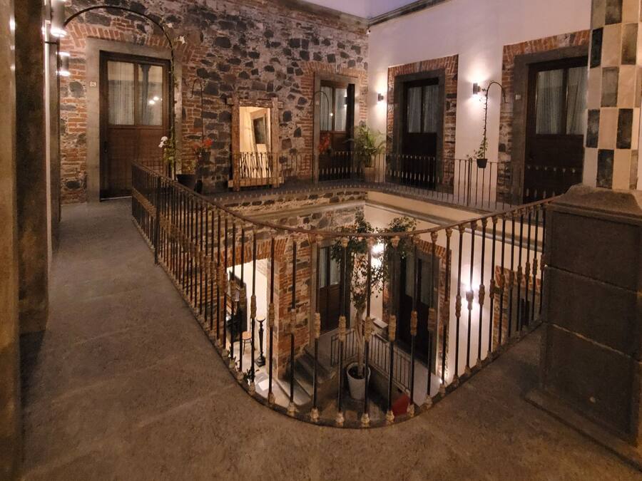 A spacious courtyard with a glass ceiling, stone walls, and a central water feature.