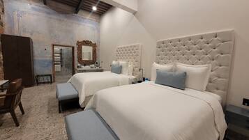 Habitación de hotel con dos camas, un espejo grande, una puerta de madera y una mesita pequeña.