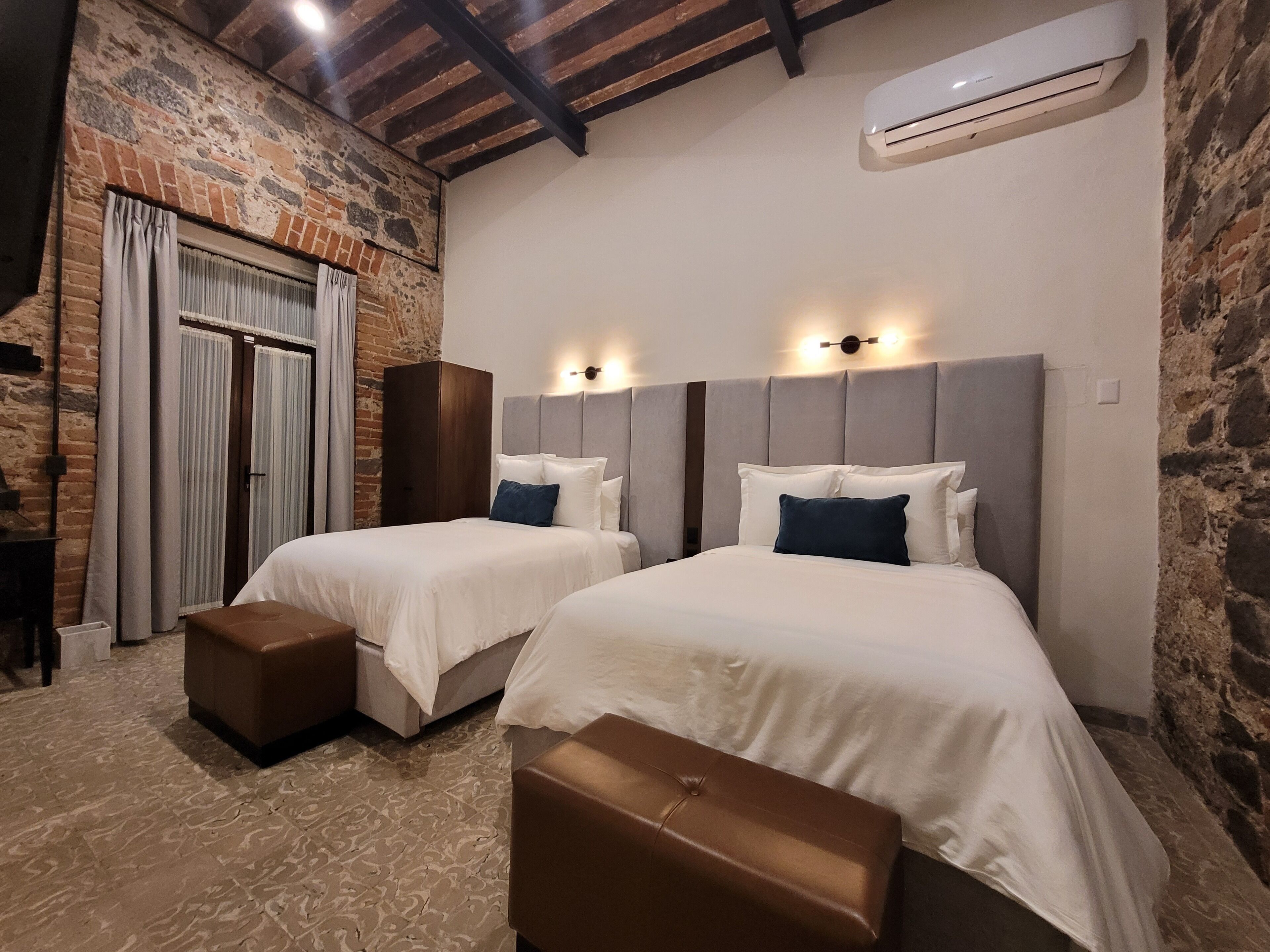 A bedroom with two beds, a wardrobe, and an air conditioning unit.