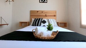Un lit bien fait, avec une tête de lit en bois, deux tables de chevet et un élément décoratif fixé au mur.