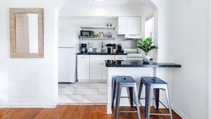 Una cocina moderna con armarios blancos, encimera negra y un letrero que dice 'BEACH HOUSE'.