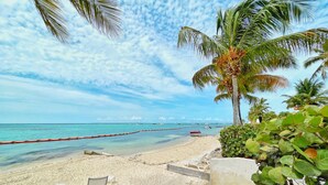 A beach with clear turquoise water, white lounge chairs, and a red barrier. - Beachfront villa private pool & stunning views (Saint-François)